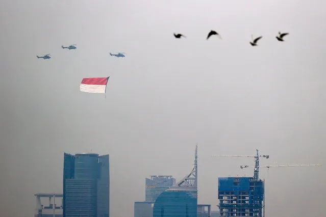 Indonesian Air Force helicopters carrying a big flag fly above high rise buildings during the country's 76th Independence Day celebrations in Jakarta, Indonesia, August 17, 2021. (Photo by Willy Kurniawan/Reuters)