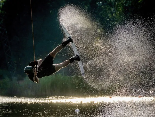 A man performs on his wakeboard on a lake in Suesel, northern Germany, late Monday, July 26, 2021. (Photo by Michael Probst/AP Photo)