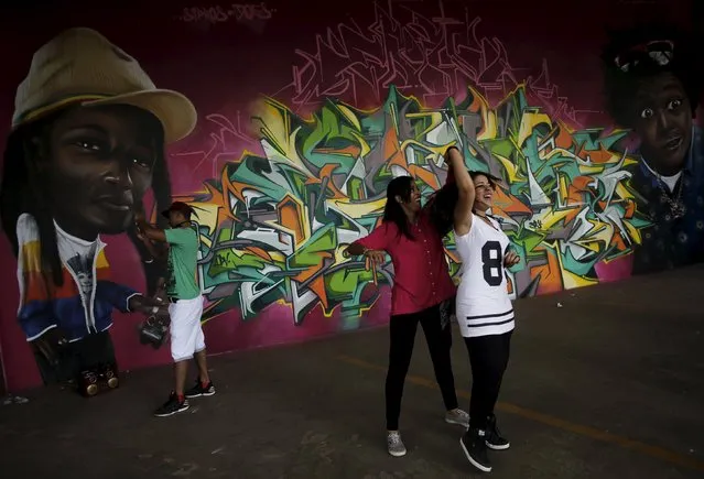Women dance in front of a work by Brazilian artist Sipros during the 3th International Biennial Fine Art Graffiti exhibition at the Ibirapuera park in Sao Paulo April 21, 2015. (Photo by Nacho Doce/Reuters)