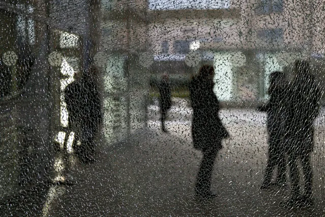 People stand behind a shattered glass outside the EU headquarters in Brussels, Wednesday, January 9, 2019. The window was shattered during a recent demonstration. (Photo by Virginia Mayo/AP Photo)