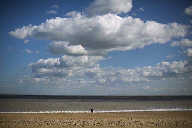 A woman walks a dog on the beach in Ramsgate, England, Tuesday, March 31, 2015. (Photo by Matt Dunham/AP Photo)