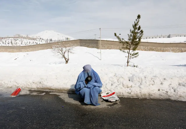 An Afghan woman clad in burqa begs in a snow-covered street on the outskirts of Kabul, Afghanistan February 6, 2017. (Photo by Mohammad Ismail/Reuters)
