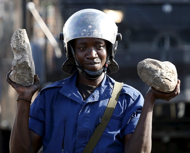 A policeman holds stones as he cleans a barricade which was set up by protesters during a protest against president Pierre Nkurunziza in Bujumbura, Burundi, May 10, 2015. East African leaders will hold a summit in Tanzania on May 13 aimed at breaking the political deadlock in Burundi and ensuring the country holds peaceful elections, Tanzania's presidency says. (Photo by Goran Tomasevic/Reuters)
