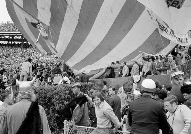 Spectators grab a large hot air balloon after it went astray before Super Bowl game in New Orleans, January 11, 1970. The Viking who was riding in the basket assembly remained there throughout the flight. (Photo by AP Photo)