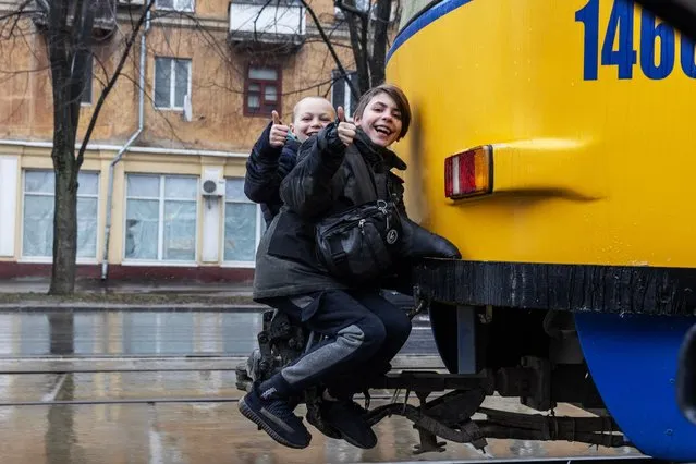Children hitch a ride with a passing tram in Dnipro, Ukraine on March 19, 2024. (Photo by Jack Hill/The Times)