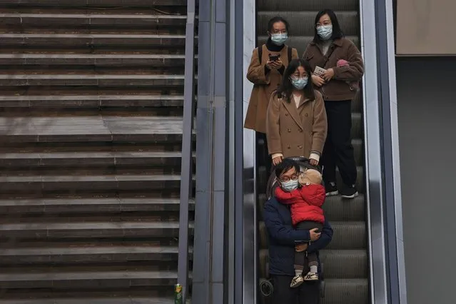 People wearing face masks to protect from COVID-19 take an escalator at a commercial office building in Beijing, Sunday, November 28, 2021. (Photo by Andy Wong/AP Photo)