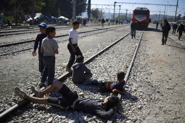 Young boys block the rail tracks to as they try to stop a train at a makeshift camp for refugees and migrants at the Greek-Macedonian border near the village of Idomeni, Greece, April 12, 2016. (Photo by Stoyan Nenov/Reuters)