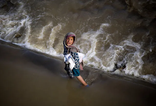 An Afghan girl takes a short cut through a streaming river on the outskirts of Kabul, Afghanistan, Wednesday, May 15, 2013. (Photo by Anja Niedringhaus/AP Photo)