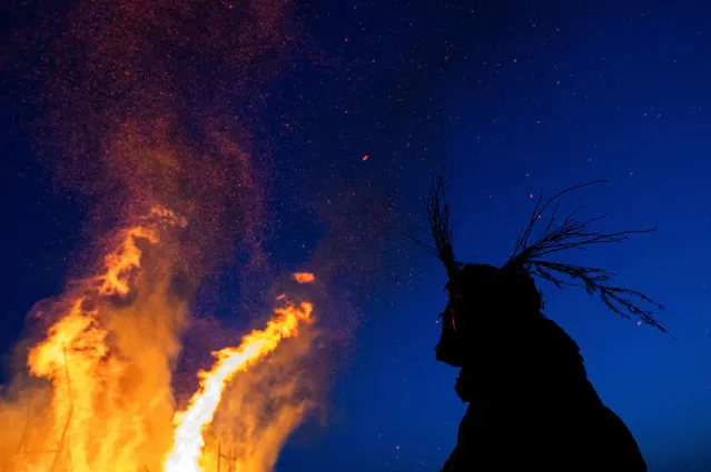 A reveller watches the burning installation called “Black Mount”, during the celebrations of Maslenitsa, a pagan holiday marking the end of the winter, in the village of Nikola-Lenivets in Kaluga region, Russia on March 16, 2024. (Photo by Maxim Shemetov/Reuters)