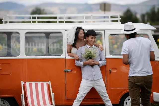 A couple poses with a bus which serves as a prop during their wedding photoshoot near Erhai in Dali Bai Autonomous Prefecture, Yunnan province, China on June 15, 2019. (Photo by Tingshu Wang/Reuters)