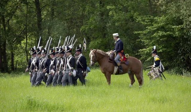 In this May 10, 2015, photo, historical re-enactors dressed as soldiers of the Belgian-Dutch 7th Battalion of the Line are commanded by a cavalry officer as they march in formation at a Napoleonic era living history camp in Elewijt, Belgium. The Belgian-Dutch living history group is coordinating their group for participation in the 200th anniversary of the Battle of Waterloo which will take place in June 2015. (AP Photo/Virginia Mayo)