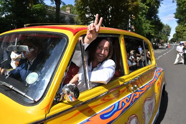 Beatles lookalike band “Fab Gear” member John Lennon waves from his replica psychedelic rolls royce after joining fans at the famous Abbey Road zebra crossing in London, England on August 8, 2019, on the 50th anniversary of the day that the iconic Beatles album cover photograph was taken. (Photo by Daniel Leal-Olivas/AFP Photo)