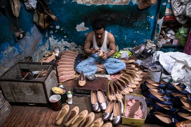 A shoemaker applies glue to a shoe in a workshop at Chawri Bazar in the old quarters of New Delhi on August 19, 2019. (Photo by Xavier Galiana/AFP Photo)