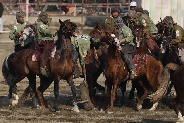 Afghan horse riders compete during a Buzkashi league match, in Kabul, Afghanistan, Sunday, February 27, 2022. Buzkashi is a popular traditional sport of Afghanistan in which horse-mounted players attempt to place a goat or calf carcass in a goal, nowadays an effigy is used instead of a carcass. During the first Taliban rule of Afghanistan Buzkashi was banned. (Photo by Hussein Malla/AP Photo)