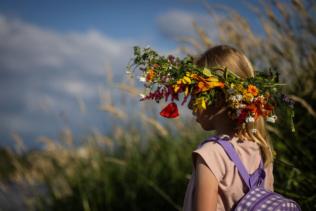 A girl wears a wreath on her head as she attends the so-called Wianki nad Wis (Wreaths over the Vistula) festival on the banks of the Vistula river in Warsaw, Poland, on June 22, 2024. The celebrations are related to the traditions and rituals of Kupala Night on summer solstice, such as making wreaths of field flowers and throwing them into the river as bringers of happiness and luck. (Photo by Wojtek Radwanski/AFP Photo)