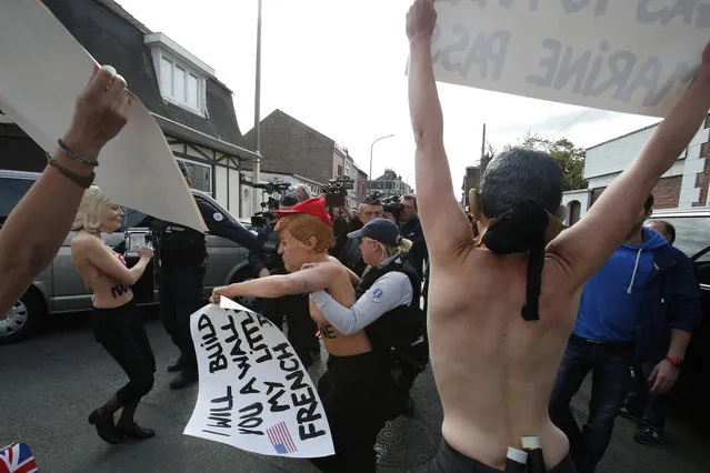 Femen activists, ones wearing the mask of Marine Le Pen, left, and U.S President Donald Trump, center, are detained as they demonstrate in Henin Beaumont, northern France, where far-right leader and presidential candidate Le Pen will vote, during the first round of the French presidential election, Sunday April 23, 2017. French voters began casting ballots for the presidential election Sunday under heightened security in a tense first-round poll that's seen as a test for the spread of populism around the world. (Photo by Michel Spingler/AP Photo)