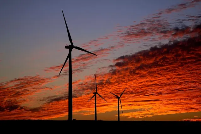 Wind turbines are silhouetted against the sky at sunset Friday, December 17, 2021, near Ellsworth, Kan. The 300-foot-tall turbines are among the 134 units comprising the Post Rock Wind Farm. (Photo by Charlie Riedel/AP Photo)
