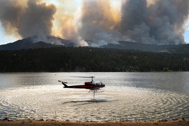 A helicopter collects water to drop on the Alexander Mountain Fire burning Monday, July 29, 2024, west of Loveland, Colo. (Photo by Helen H. Richardson/The Denver Post via AP Photo)