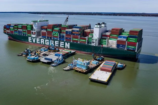A tugboat pushes a barge full of containers away from the Ever Forward container ship in Pasadena, Maryland, on April 11, 2022, as the cargo ship sits in the Chesapeake Bay after it ran aground near Baltimore. - Container removal began April 9, 2022, as part of the Ever Forward boxship refloat operation in Chesapeake Bay. The process, using barges alongside, will continue in daylight hours throughout this week with four to five containers being offloaded per hour in the complex operation. (Photo by Jim Watson/AFP Photo)