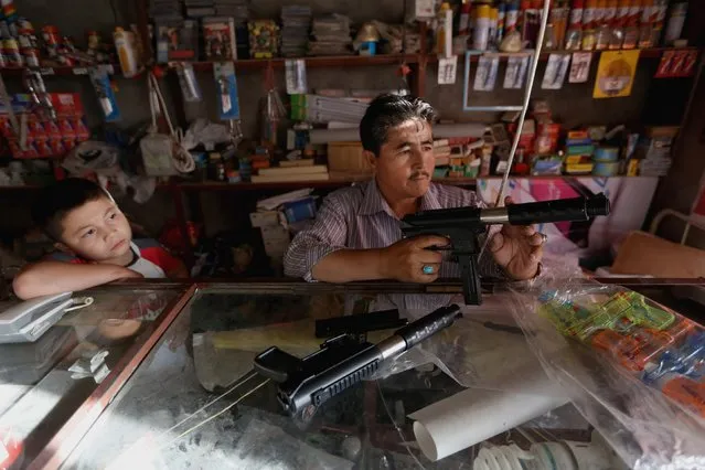In this Saturday, July 25, 2015 photo, Murad Ali Gharibyar 45, an Afghan toy guns salesman holds a toy at his shop, in Kabul, Afghanistan. (Photo by Rahmat Gul/AP Photo)
