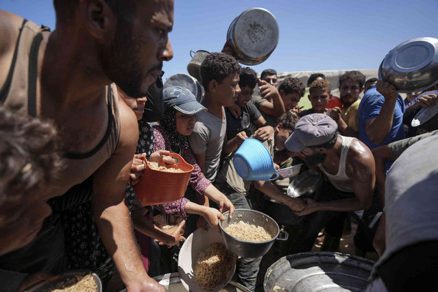 Displaced Palestinians gather for food distribution in Deir al Balah, central Gaza Strip, Friday, August 23, 2024. (Photo by Abdel Kareem Hana/AP Photo)