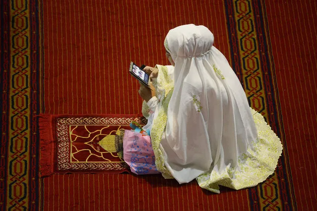 This picture taken on June 7, 2016 shows an Indonesian Muslim woman checking her phone while attending prayers on the third night of the holy month of Ramadan at the Istiqlal grand mosque in Jakarta. Islam's holy month of Ramadan is celebrated by Muslims worldwide marked by fasting, abstaining from foods, s*x and smoking from dawn to dusk for soul cleansing and strengthening the spiritual bond between them and the Almighty. (Photo by Adek Berry/AFP Photo)