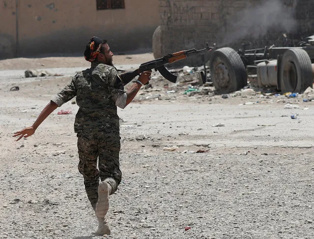 A Kurdish fighter from the People's Protection Units (YPG) fires his rifle at Islamic State militants as he runs across a street in Raqqa, Syria July 3, 2017. (Photo by Goran Tomasevic/Reuters)