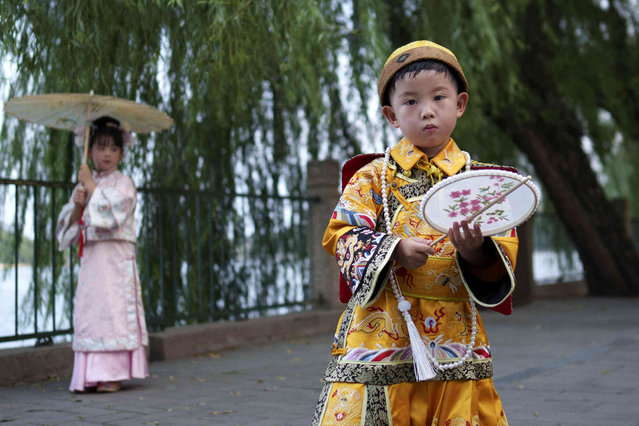 Chinese children dressed in Qing Dynasty royal attire stands for photographs at Beihai park in Beijing, China, Sunday, July 28, 2024. (Photo by Vincent Thian/AP Photo)