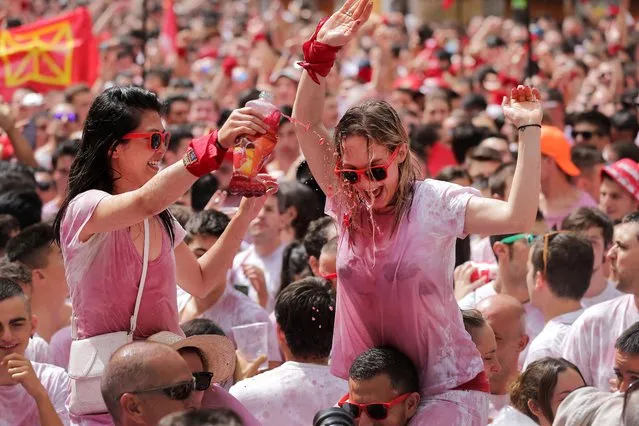 Two revellers douse themselves with wine as they celebrate the “Chupinazo” (start rocket) to mark the kickoff at noon sharp of the San Fermin Festival, in front of the Town Hall of Pamplona, northern Spain, on July 6, 2017. A red-and-white sea of revellers soaked each other with wine in a packed Pamplona square today to kick off Spain's most famous fiesta, the San Fermin bull-running festival. (Photo by Cesar Manso/AFP Photo)