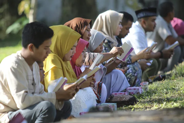 People read the holy book of the Quran as they pray at a mass grave site for the victims of the Indian Ocean tsunami, during the commemoration of the 15th anniversary of the disaster in Banda Aceh, Indonesia, Thursday, December 26, 2019. (Photo by Nurhasanah/AP Photo)