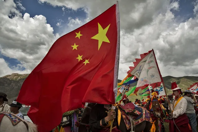 An ethnic Tibetan nomad carries a China flag while waiting to perform skills during a riding competition at a government sponsored local festival on July 26, 2015 on the Tibetan Plateau in Yushu County, Qinghai, China. (Photo by Kevin Frayer/Getty Images)