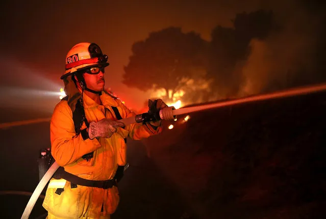 A firefighter sprays water on the Detwiler Fire on July 18, 2017 in Mariposa, California. (Photo by Justin Sullivan/Getty Images)