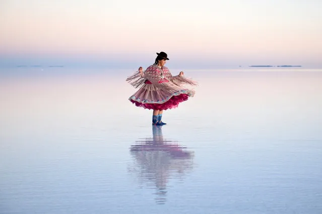 A woman in a Cholita dress poses for photos, at the Uyuni Salt Flat in Bolivia on March 26, 2022. (Photo by Claudia Morales/Reuters)