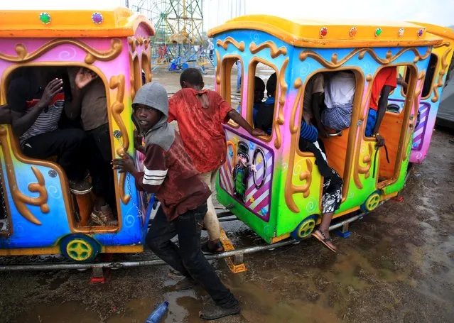 Children play with an amusement train ride during heavy rain during the Maralal Camel Derby, Kenya, August 15, 2015. (Photo by Goran Tomasevic/Reuters)