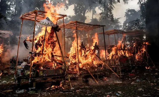 Sarcophagi burn at a cremation site during a mass cremation in Ubud, Bali, Indonesia, on August 1, 2014. More than 100 corpses were collectively cremated in the ceremony known as Ngaben Masal (Mass Cremation). Taking place every 4 years in Singakerta Village, it is one of the most important ceremonies for Balinese Hindu people. They believe that during the burnings the spirits of the deceased will be freed to reincarnate. (Photo by Agung Parameswara/Getty Images)