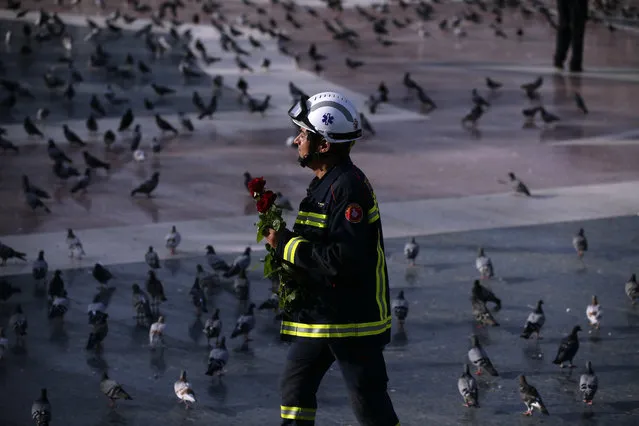 A firefighter holding roses walks in Barcelona's Plaza Catalonia during a demonstration condemning the attacks that killed 15 people last week in Barcelona, Spain, Saturday, August 26, 2017. The Islamic State group has claimed responsibility for the attacks on Aug. 17-18 in Barcelona and Cambrils that also left more than 120 injured. Eight suspects are dead and four more under investigation, two of them in jail. (Photo by Manu Fernandez/AP Photo)