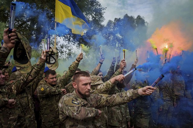Ukrainian servicemen of the Azov brigade light flares during the funeral ceremony of fallen comrade Ihor Kusochek, in Travkine, Chernihiv region, Ukraine, Friday October 4, 2024. (Photo by Evgeniy Maloletka/AP Photo)
