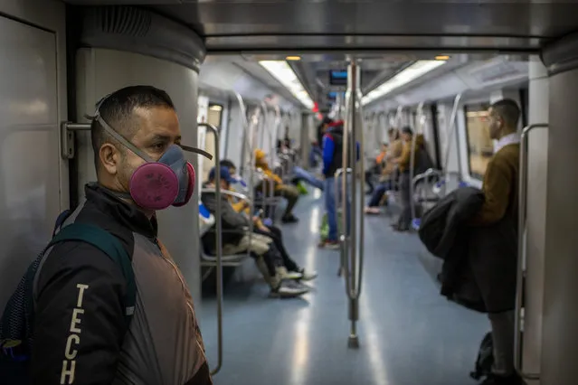 A man wearing a face mask travels by train in Barcelona, Spain, Wednesday, March 18, 2020. Spain will mobilize 200 billion euros or the equivalent to one fifth of the country's annual output in loans, credit guarantees and subsidies for workers and vulnerable citizens, Prime Minister Pedro Sánchez announced Tuesday. (Photo by Emilio Morenatti/AP Photo)
