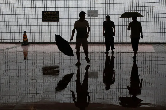 People are reflected on the wet floor of an underpass on a day of heavy rain in Beijing, China, July 20, 2016. (Photo by Thomas Peter/Reuters)