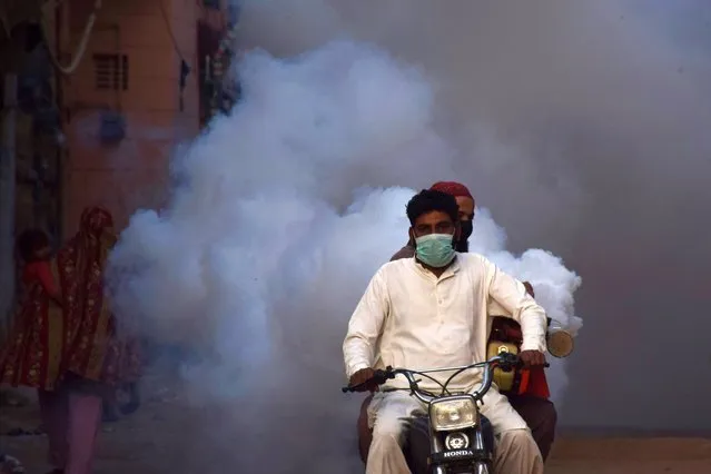 Health workers on motor-bike fumigate, as a preventive measure against coronavirus, along a street in Hyderabad, Pakistan on March 15, 2020. (Photo by Yasir Ali/Reuters)