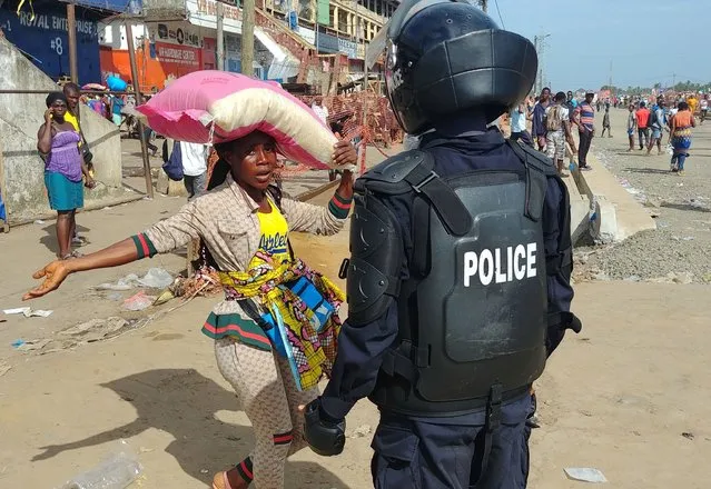 A police officer chases shoppers to clear the streets of the Red Light market on the first day of lockdown to stop the spread of the coronavirus disease (COVID-19) in Monrovia, Liberia on April 11, 2020. (Photo by Derick Snyder/Reuters)