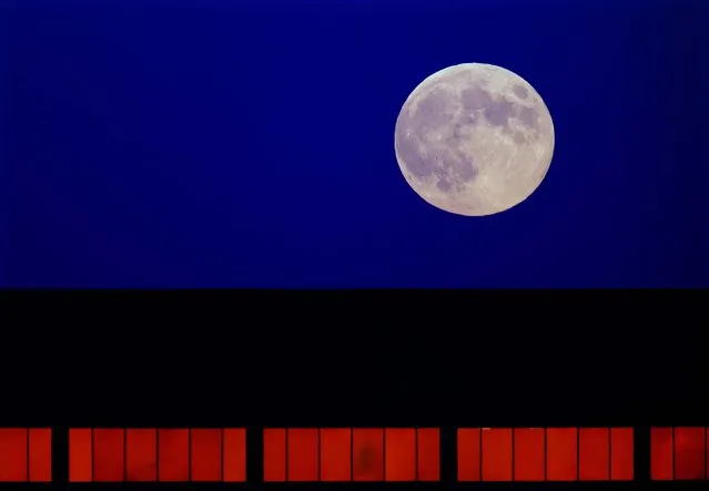 The moon rises over a downtown office building in Springfield, Illinois. (Photo by Seth Perlman/AP Photo)