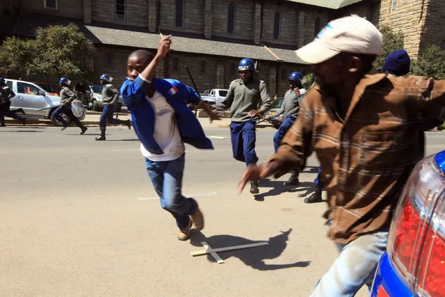 Zimbabwe police officers clash with protestors and journalists, in Harare, Wednesday, August 3, 2016.  Zimbabwe police have fired tear gas and water cannons to break up anti-government protests in the capital, Harare. Police beat up several journalists covering the protests Wednesday, smashing a video camera and attacking a journalist's car, breaking windows and taking a laptop. (Photo by Tsvangirayi Mukwazhi/AP Photo)