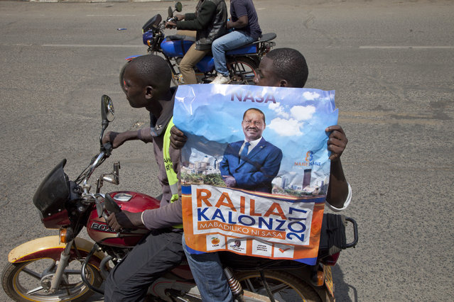 National Super Alliance (NASA) supporters holding poster of opposition leader Raila Odinga ride of a bike as they demonstrate in Nairobi, Kenya, Wednesday October 11, 2017. The protesters are demanding a change of leadership at the country's election commission. The protests took place in the capital Nairobi and the opposition stronghold of Kisumu, in western Kenya, as well as in the coastal city of Mombasa. (Photo by Sayyid Abdul Azim/AP Photo)