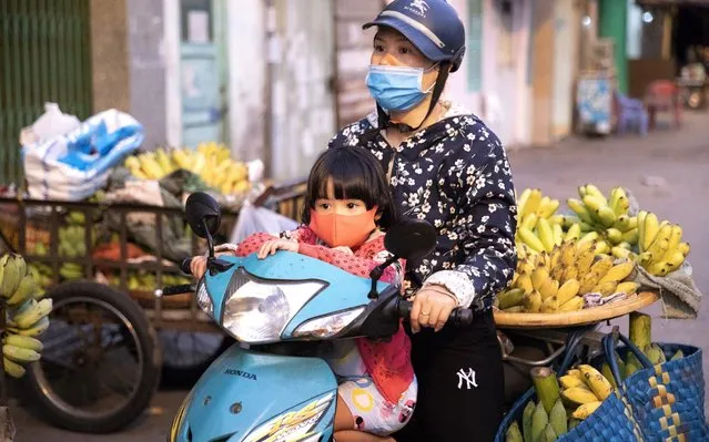 A woman and a child wearing protective mask sit on a motorcycle at Ton That Thuyet market during a partial lockdown imposed due to the coronavirus in Ho Chi Minh city, Vietnam on April 1, 2020. (Photo by Maika Elan/Bloomberg)
