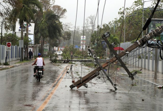 A man on a motorcycle rides past fallen power lines in the aftermath of Hurricane Fiona in Higuey, Dominican Republic on September 19, 2022. (Photo by Ricardo Rojas/Reuters)