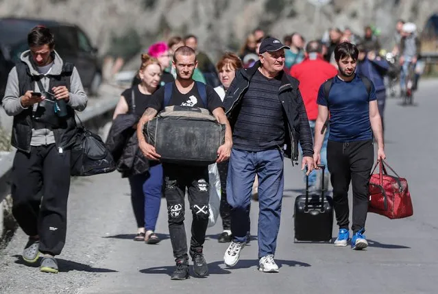 Russian men and women with their luggage walk along a road after passing through customs at the Georgia-Russia border checkpoint of Verkhnii Lars, Georgia, 27 September 2022. Thousands of Russian men left Russia after Russian President Putin announced in a televised address to the nation on 21 September, that he signed a decree on partial mobilization in the Russian Federation due to the conflict in Ukraine. Russian Defense Minister Shoigu said that 300,000 people would be called up for service as part of the move. Georgian Interior Minister Vakhtang Gomelauri said on 27 September, that in recent days some 10,000 Russians have crossed the border with Georgia every day. On 24 February 2022 Russian troops entered the Ukrainian territory in what the Russian president declared a 'Special Military Operation', starting an armed conflict that has provoked destruction and a humanitarian crisis. (Photo by Zurab Kurtsikidze/EPA/EFE/Rex Features/Shutterstock)