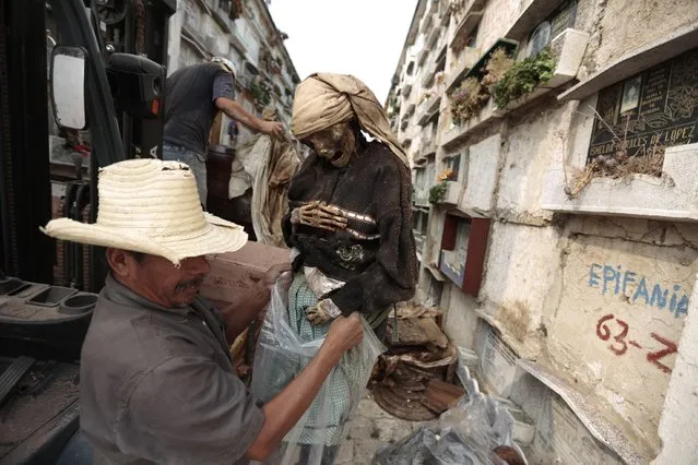 A grave cleaner holds the mummified body of a woman during exhumation works at the Verbena cemetery in Guatemala City April 17, 2013. (Photo by Jorge Dan Lopez/Reuters)
