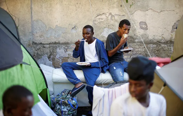 Migrants eat after getting food from volunteers at a makeshift camp in Via Cupa (Gloomy Street) in downtown Rome, Italy, August 1, 2016. (Photo by Max Rossi/Reuters)