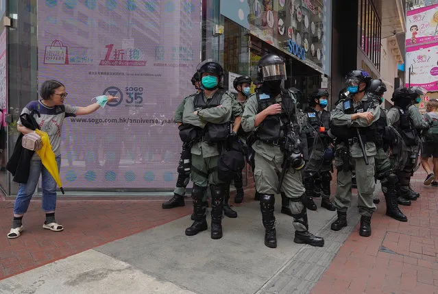 Riot police standing guard as a woman tries to cross the street in the Central district of Hong Kong, Wednesday, May 27, 2020. (Photo by Vincent Yu/AP Photo)